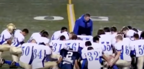Coach Joe Kennedy praying with team